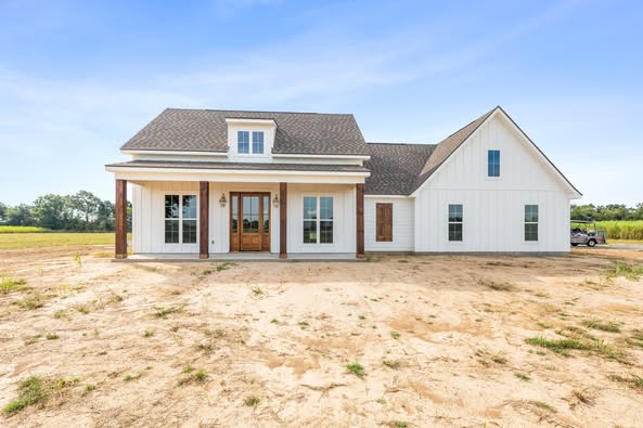 Single-story white house with a gabled roof, wood accents, and large windows. Set on an open plot with a clear blue sky, conveying serenity.
