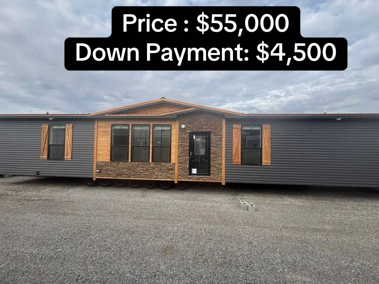A modern mobile home with wooden accents and large windows, set on gravel under a cloudy sky. Text overlay shows price $55,000, down payment $4,500.
