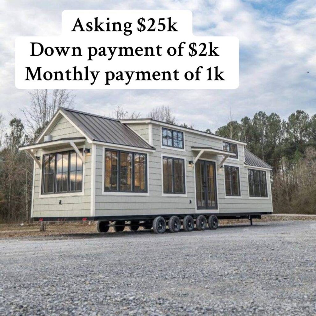 Tiny house on wheels with gray siding and multiple windows, situated on a gravel lot. Text above details sale price and payment terms. Cloudy sky behind.
