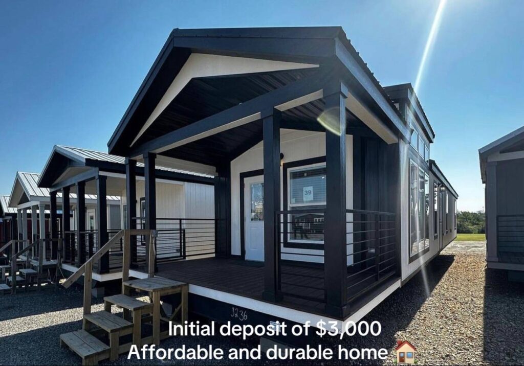 A modern, black and white modular home with a spacious porch and large windows is showcased on a sunny day. Text reads: "Initial deposit of $3,000. Affordable and durable home."