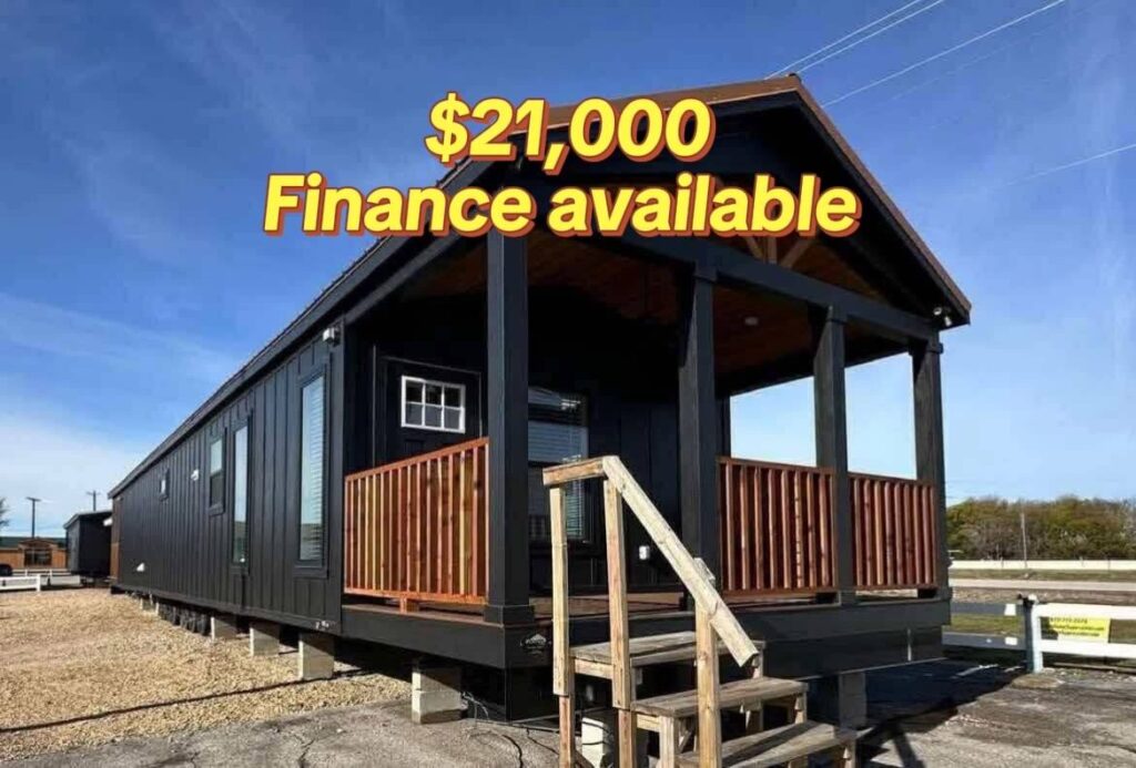 Black tiny house with wooden porch railing under a clear blue sky. Bold yellow text reads "$21,000 Finance available," suggesting affordability.